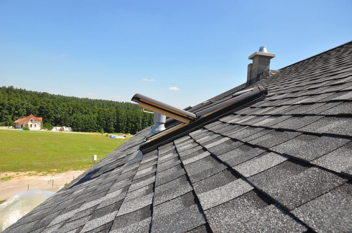 Asphalt shingles roof with open attic skylight window and unfinished roof chimney